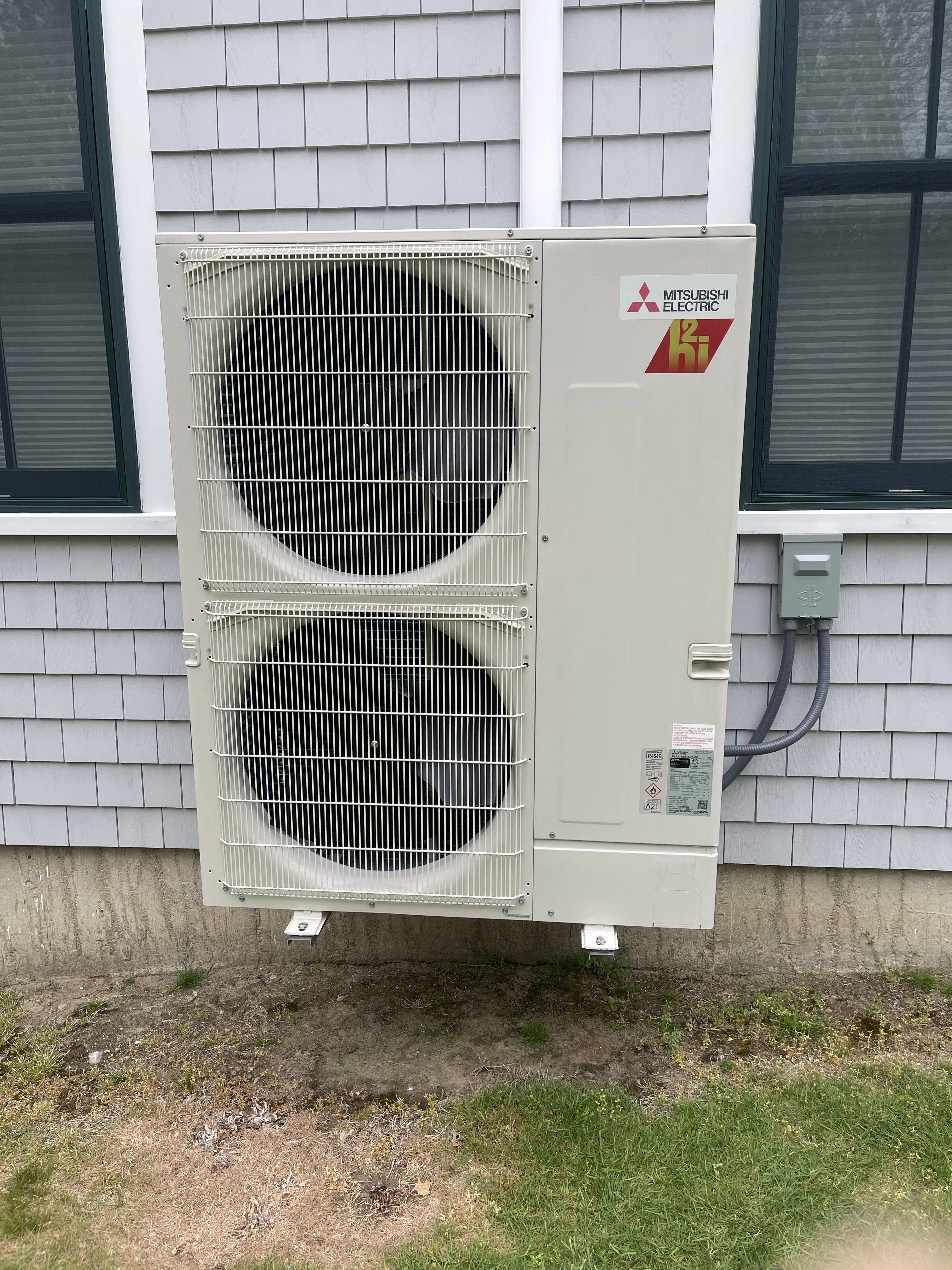 Mitsubishi Electric dual heat pump condenser units with aluminum fins mounted on concrete pad
