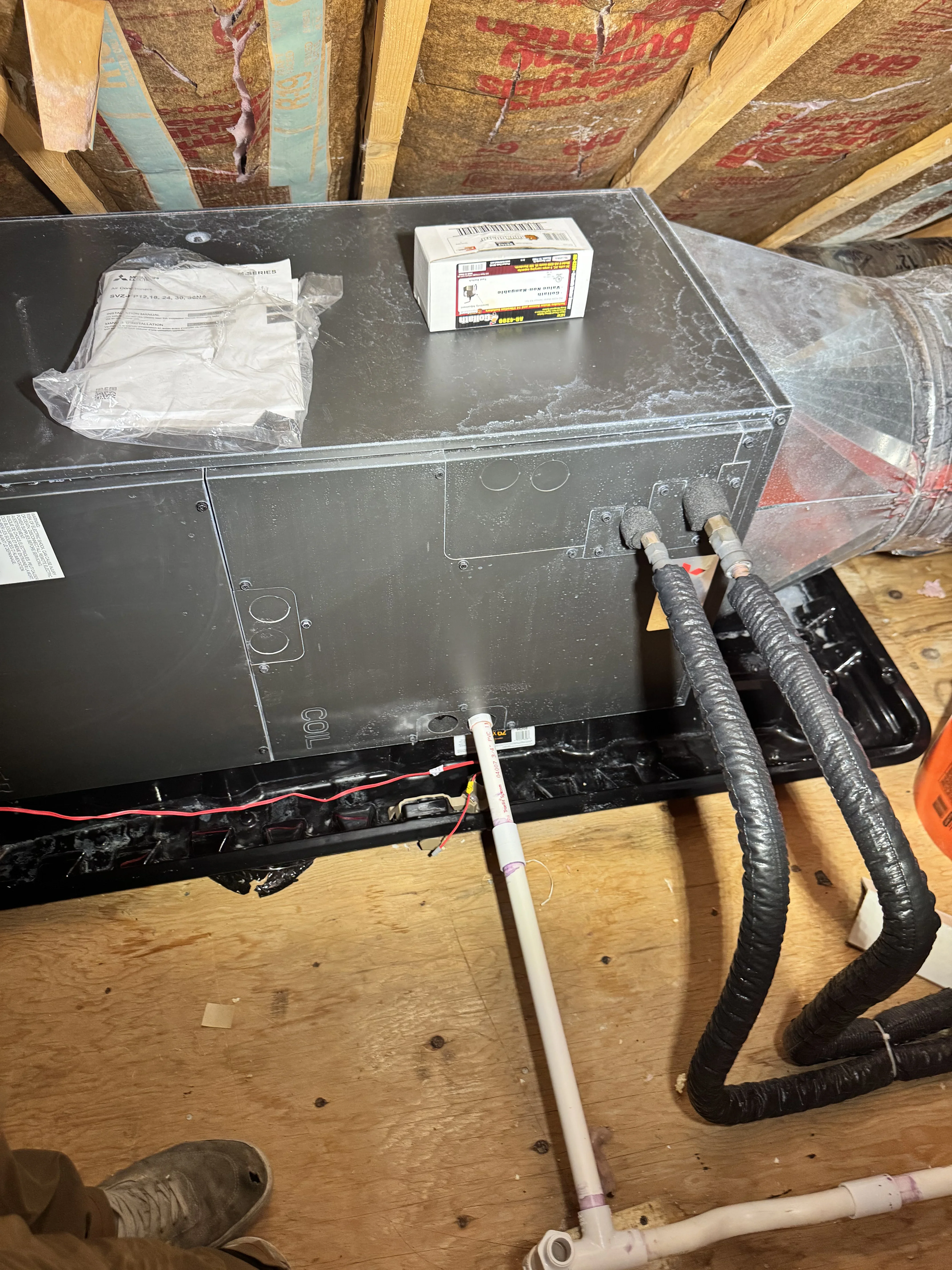 HVAC air handler unit with insulated ductwork, electrical wiring, and mounting hardware during installation