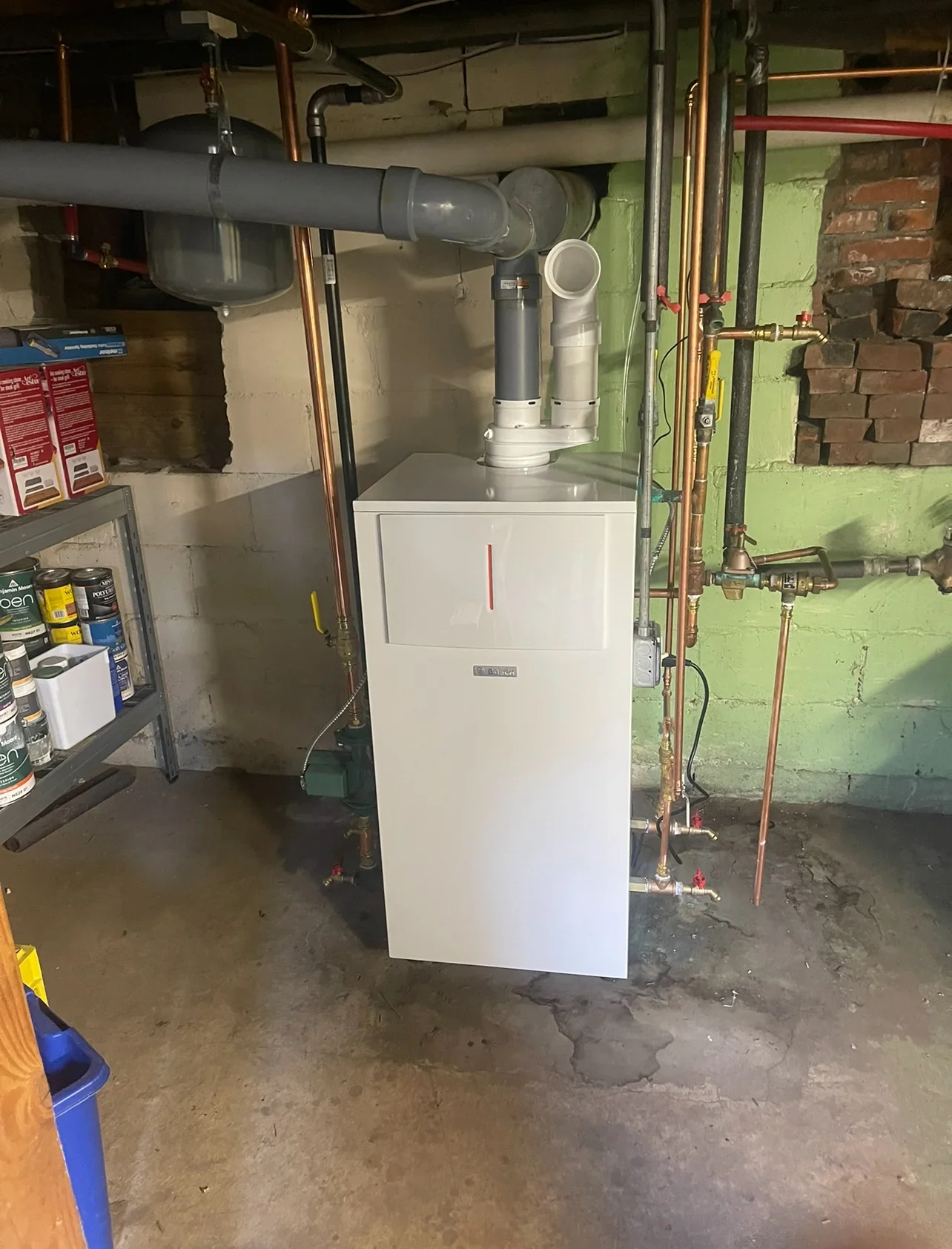 White condensing boiler with gray vent pipe and copper supply lines in basement utility room