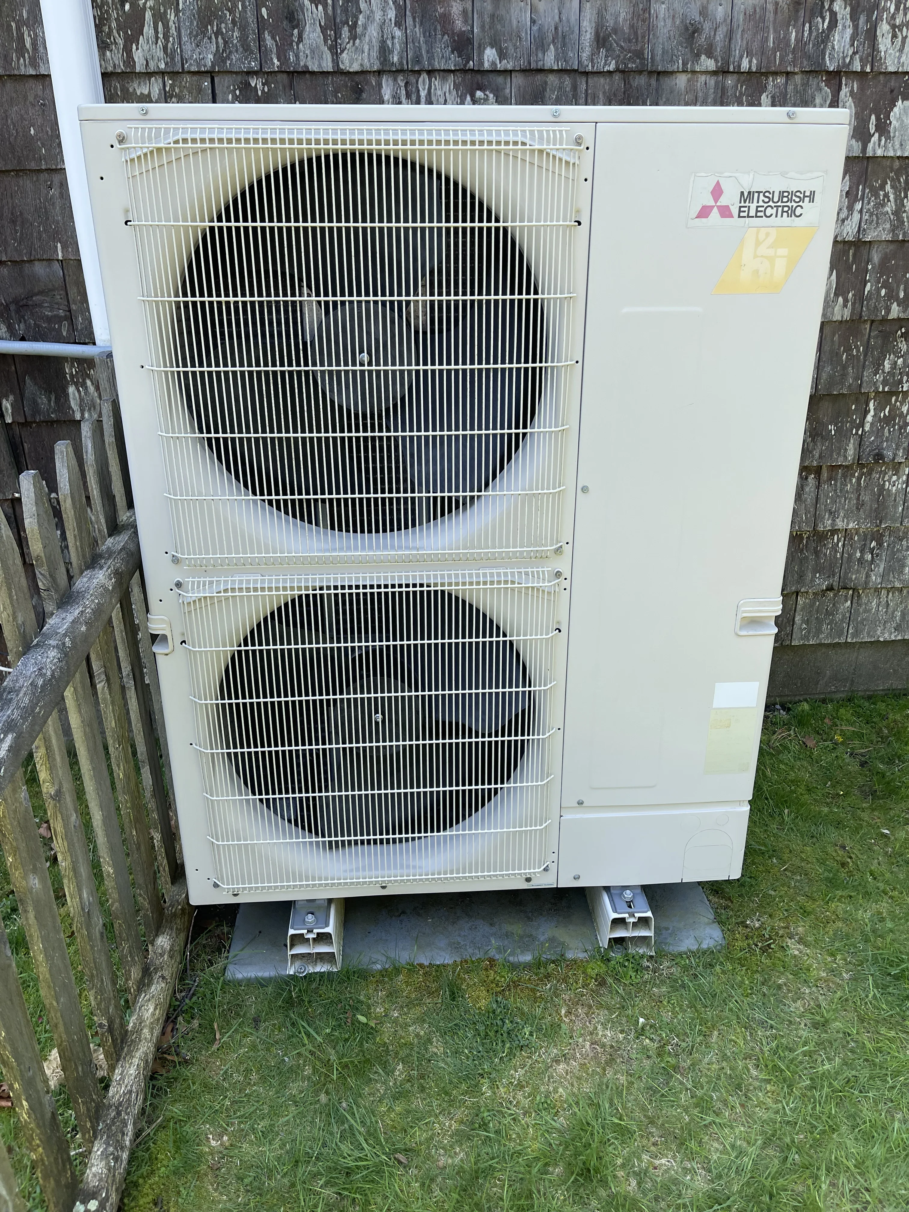 Mitsubishi Electric heat pump outdoor unit with dual fans installed on concrete pad