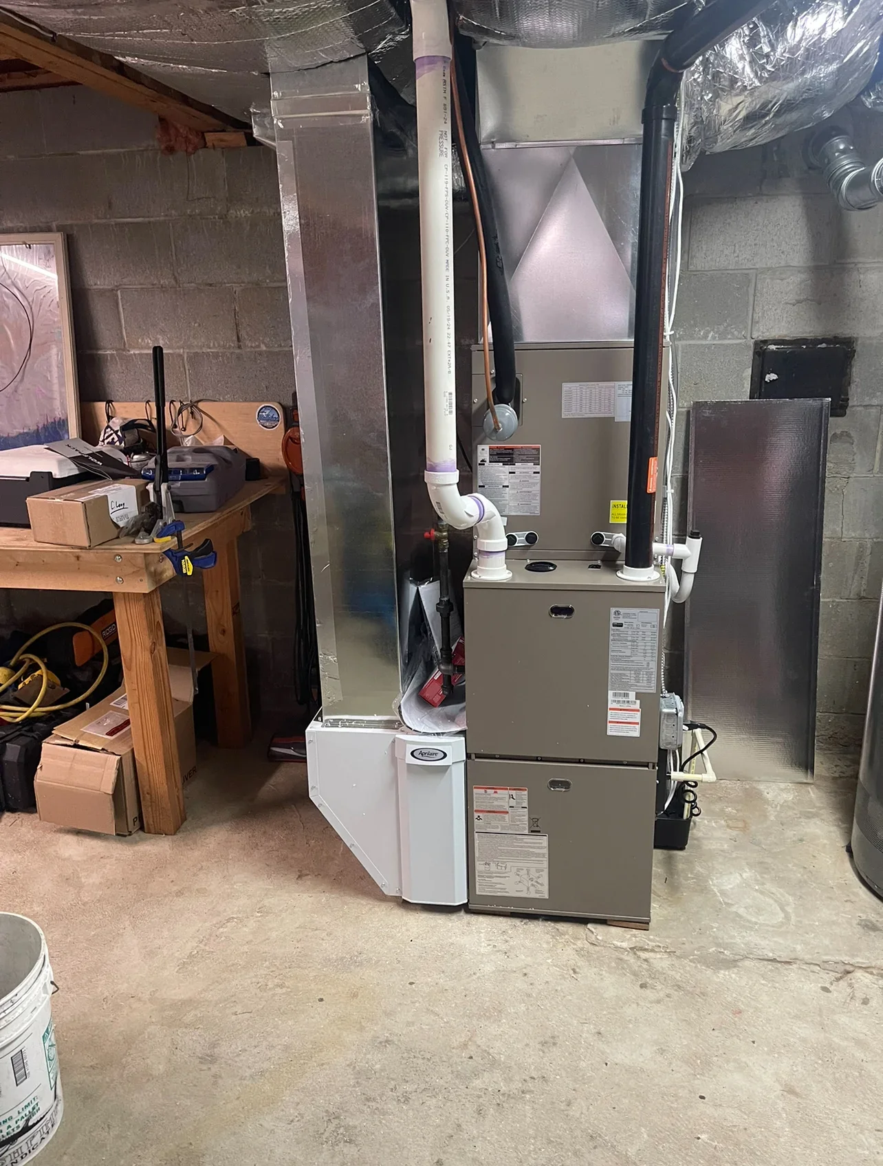 New gas furnace and air handler unit installed in basement with white PVC venting and ductwork