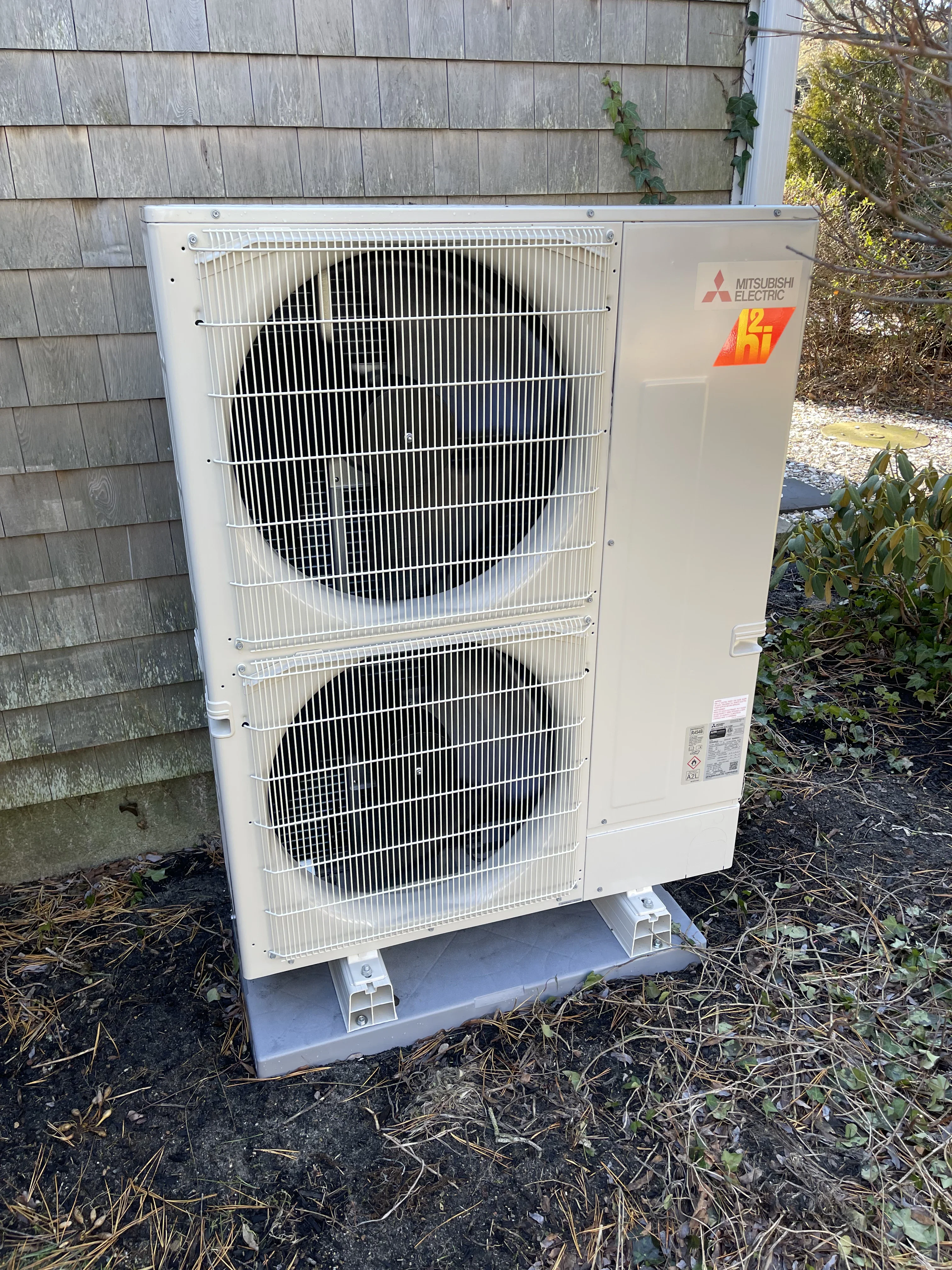 Mitsubishi Electric outdoor heat pump condenser unit with dual fan coils mounted on concrete pad