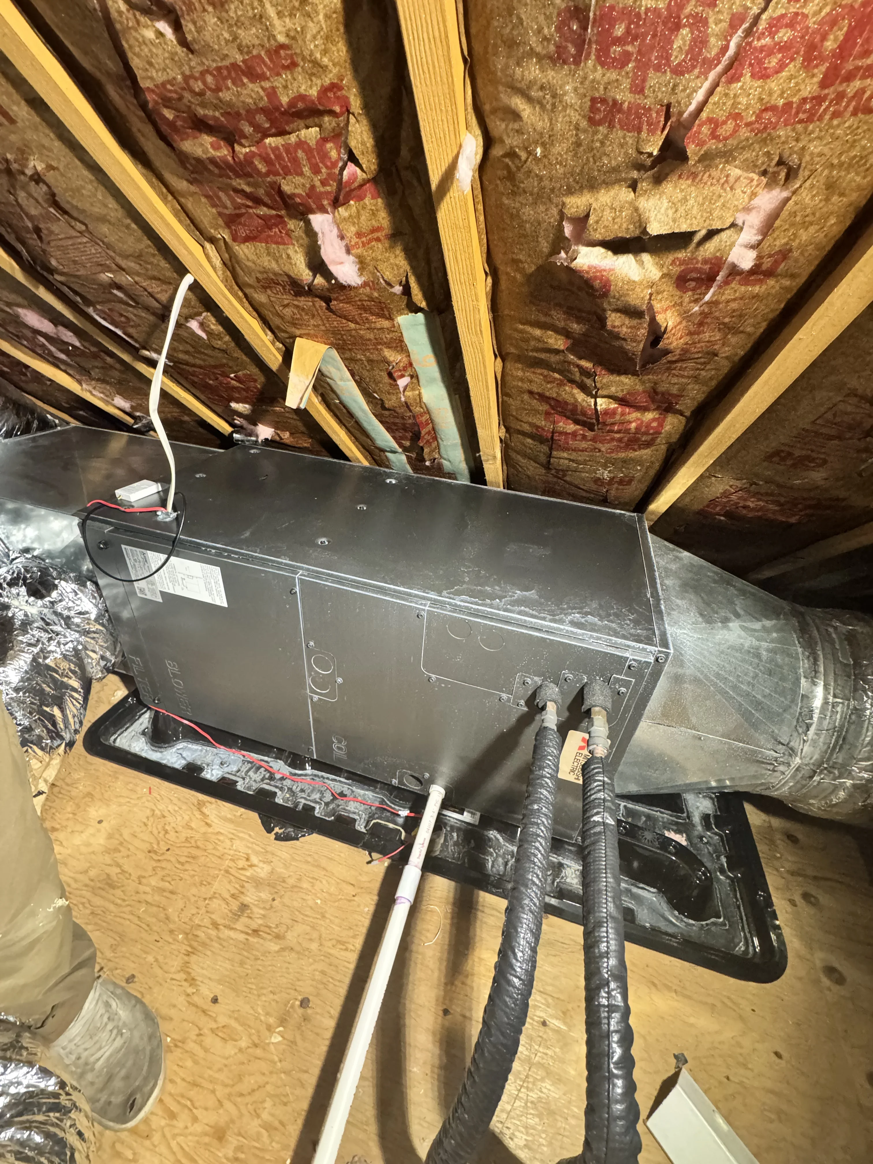 New HVAC unit installed in attic with wrapped ductwork, insulation, and electrical connections