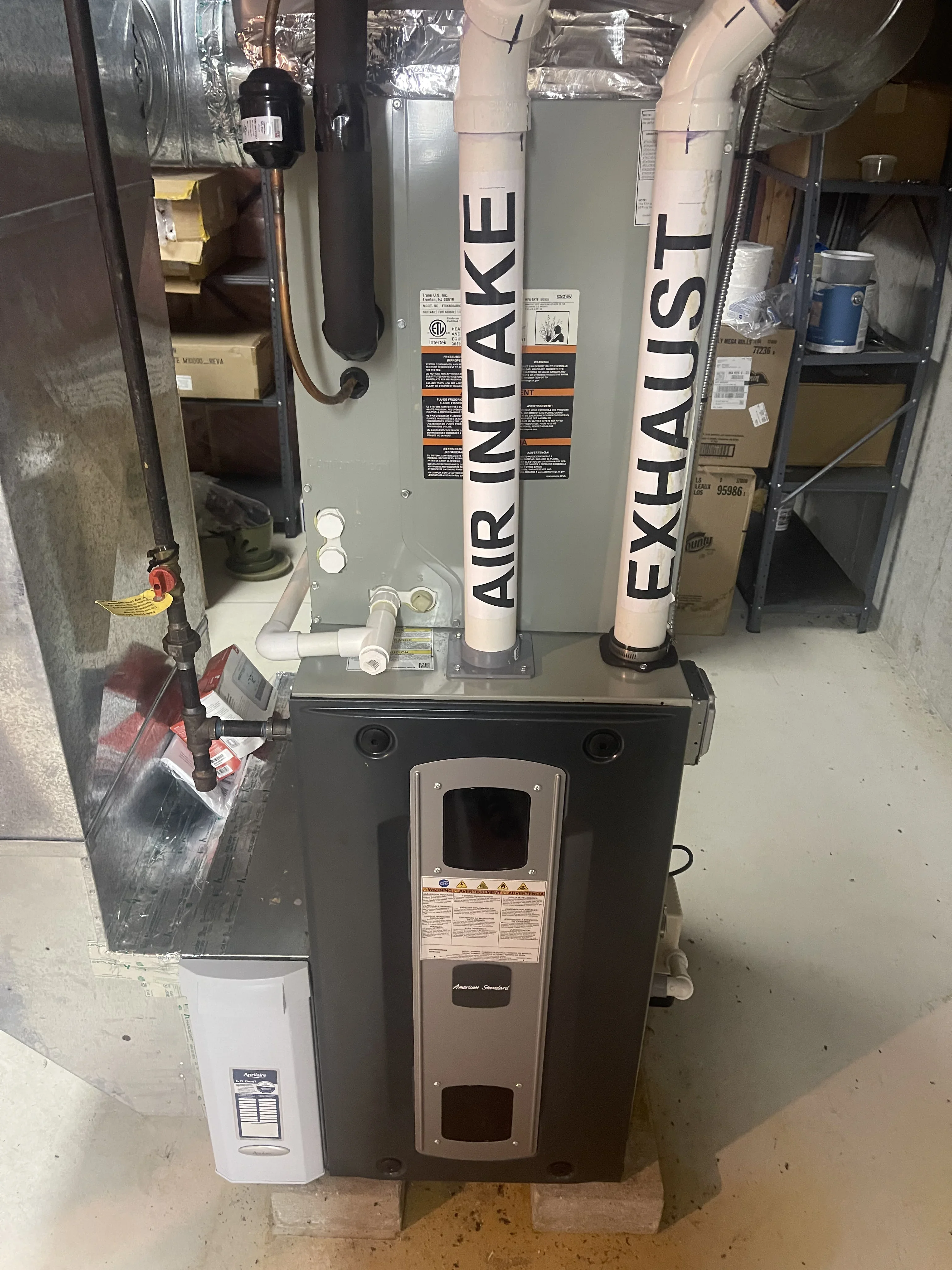 HVAC air intake and exhaust system with dual PVC pipes, filter housing, and condensate drainage installed in mechanical room