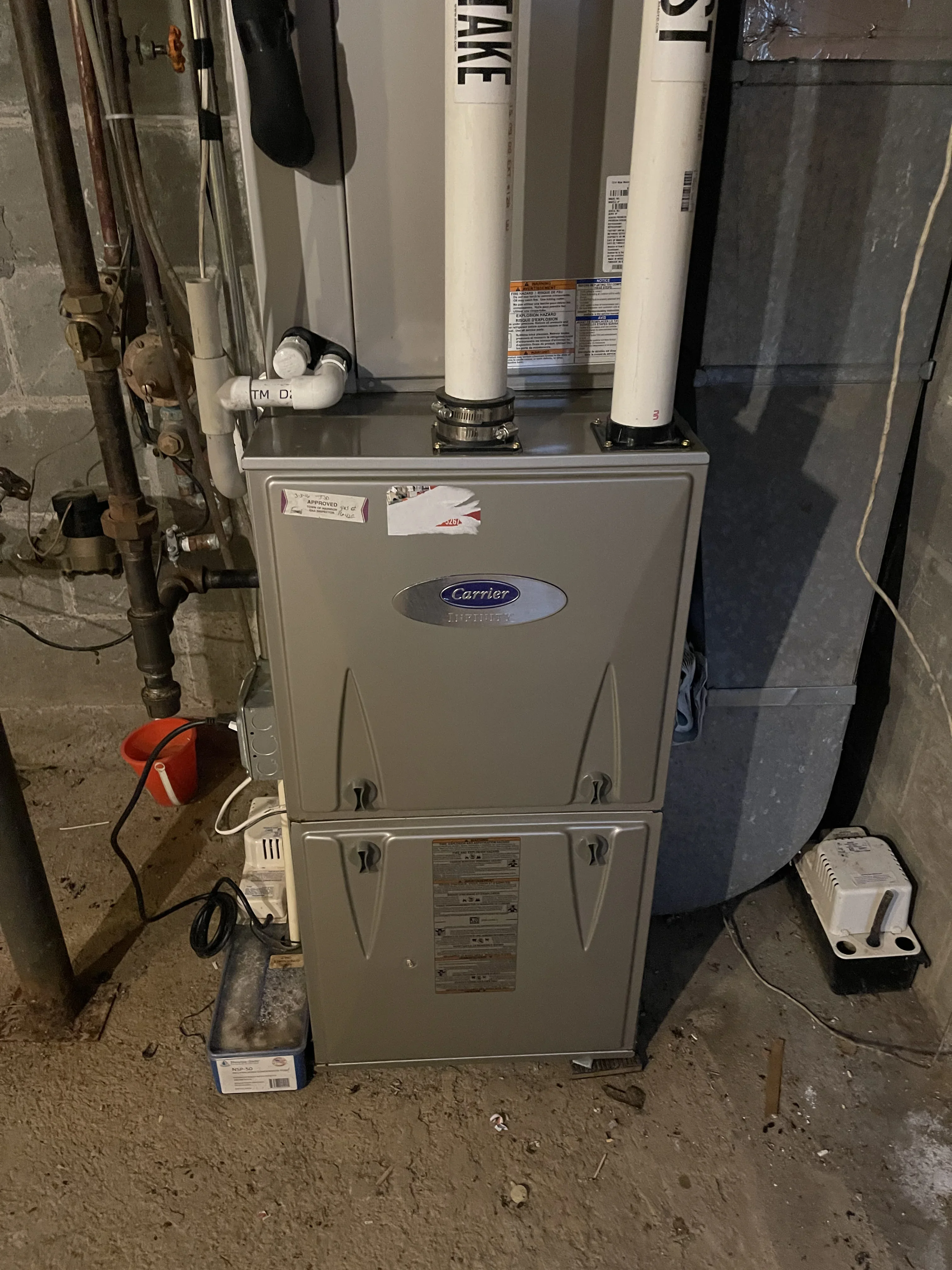 Carrier gas furnace with white metal cabinet, dual supply ducts, and basement installation